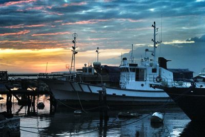 Boats at harbor against cloudy sky