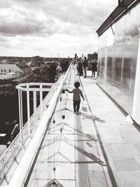 Rear view of boy walking by railing on terrace at printemps haussmann