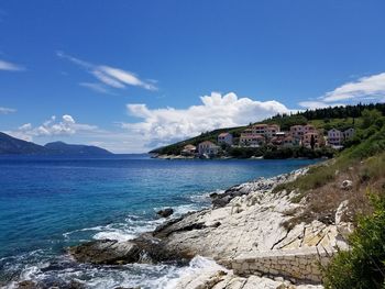 Scenic view of sea by buildings against sky