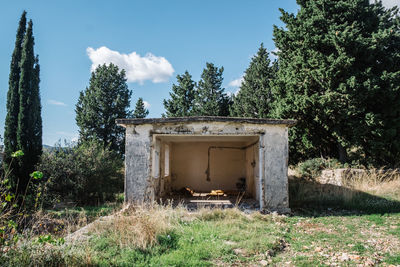 Old ruin on field against trees in forest against sky