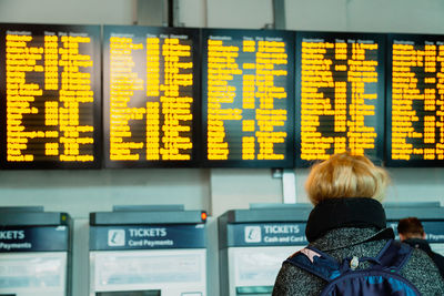 Young woman looking at the information board of travel schedules, checking her destination