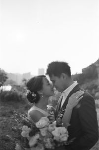 Side view of couple kissing against the sky