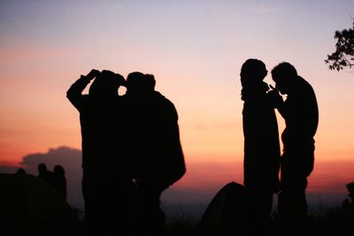 Silhouette people standing on mountain against sky during sunset