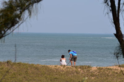 People on sea shore against sky