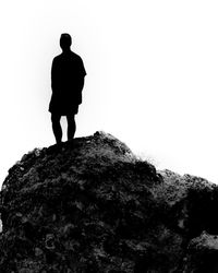Rear view of silhouette man standing on rock against sky