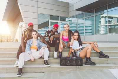 Dancers sitting on steps against building in city