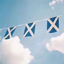 Low angle view of blue flags hanging against sky