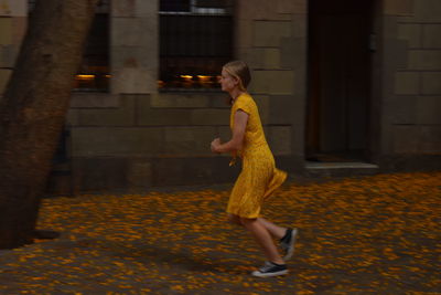 Side view of woman walking with yellow umbrella