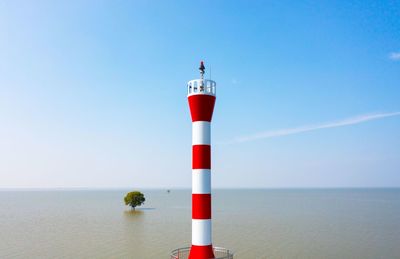 Lighthouse by sea against sky