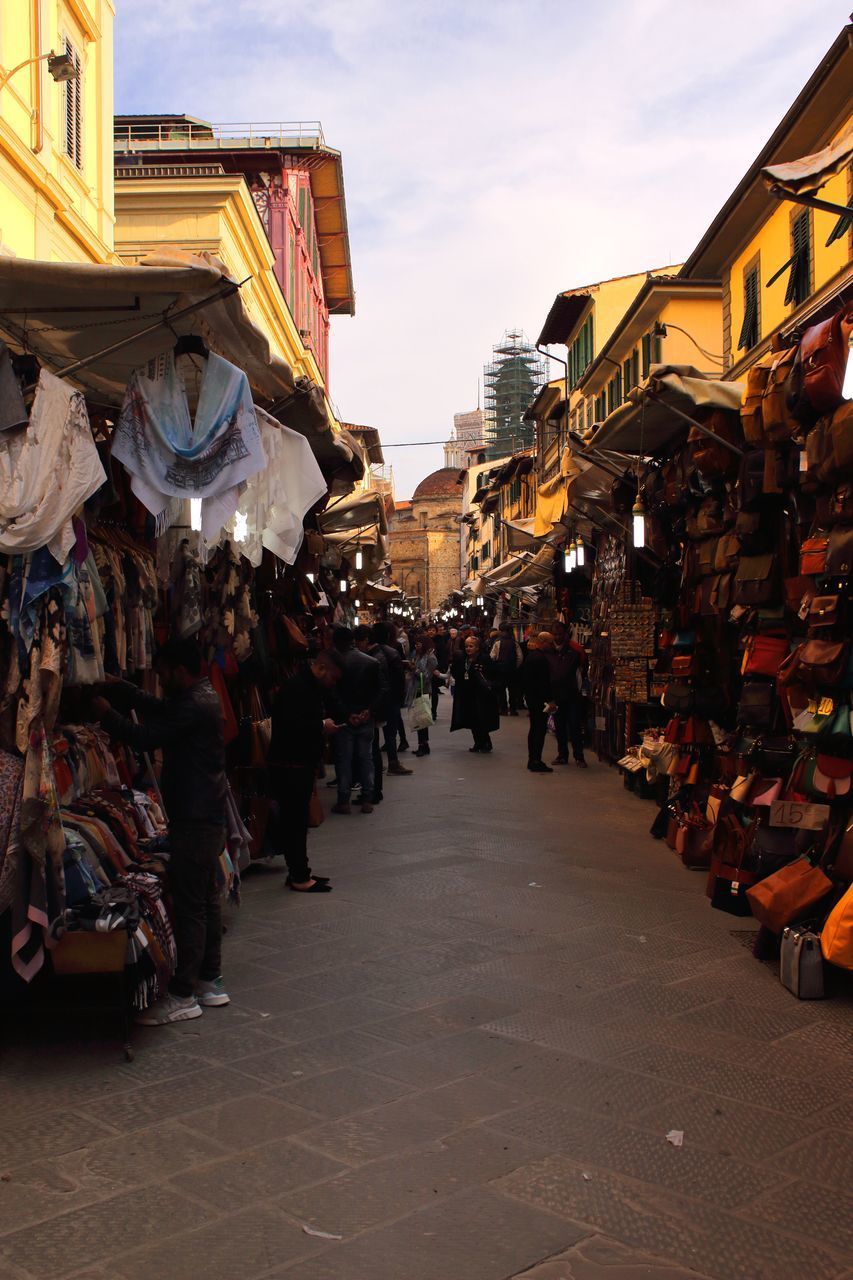 GROUP OF PEOPLE AT MARKET STALL IN CITY