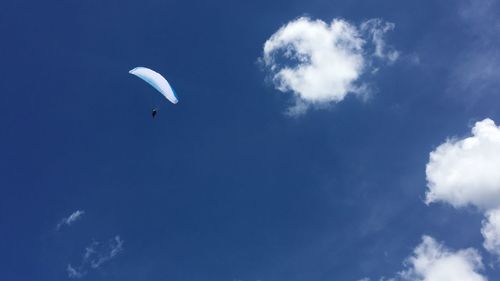 Low angle view of paragliding against blue sky