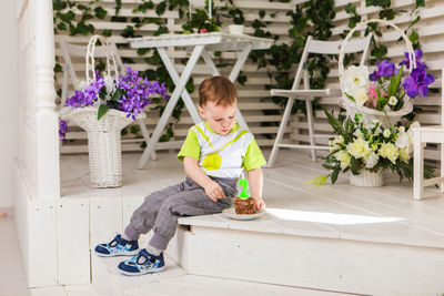 Full length of boy sitting on purple flowering plants