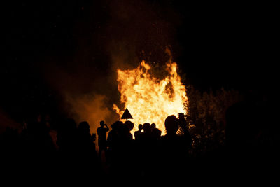 Silhouette people against fire at night