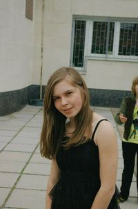 Portrait of teenage girl woman with long blond hair standing outside building