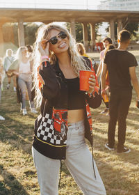 Playful happy woman with drink standing at music festival