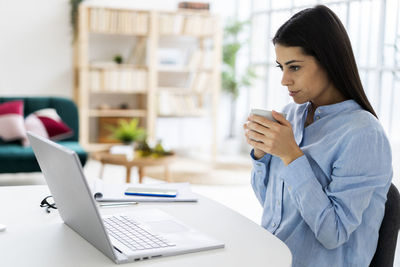 Woman using mobile phone at table