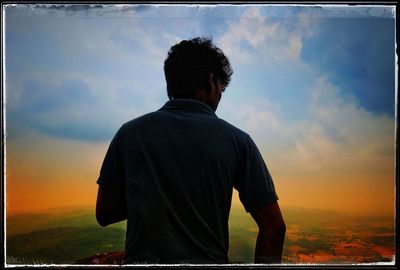 Rear view of man standing against sky during sunset