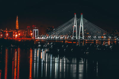 Illuminated bridge over river at night