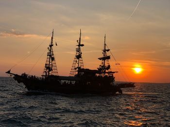 Sailboats in sea against sky during sunset