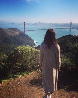 Rear view of woman standing by sea against sky