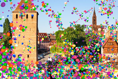 Multi colored balloons on building against sky