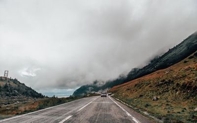 Road by mountains against sky