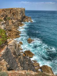 Scenic view of sea by cliff against sky