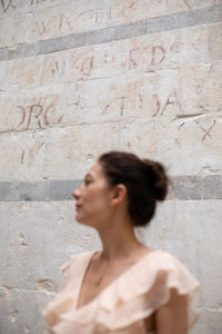 Woman looking away against wall