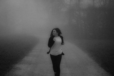 Woman running on footpath in park during foggy weather