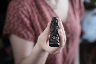 Midsection of woman holding smoking pipe