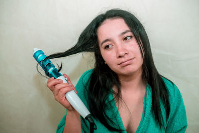 Close-up of young woman holding curling tongs