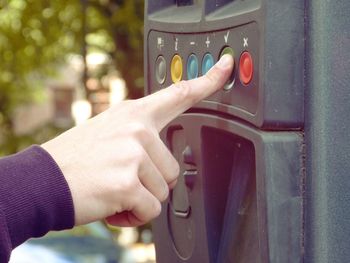 Cropped hand of person pressing button on machine