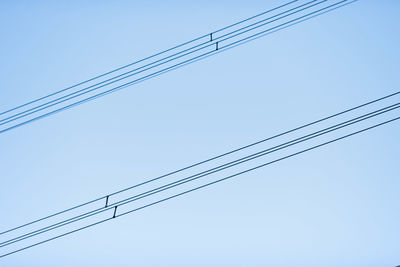 Low angle view of power cables against clear sky