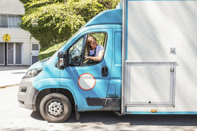 Confident young female owner driving food truck seen through window