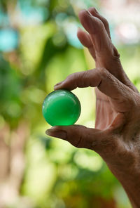 Cropped hand of person holding crystal bali outdoors