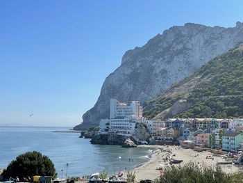 Scenic view of sea and mountains against clear blue sky