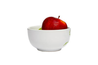 Close-up of apple fruit in bowl against white background