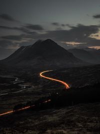 Light trails on mountain against sky at night