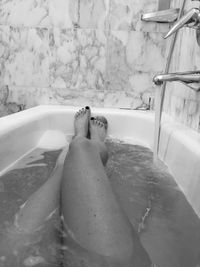 Low section of woman relaxing in bathroom