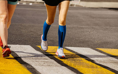 Legs two female runners run in pedestrian crossing