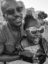 Happy father and daughter wearing sunglasses while looking away