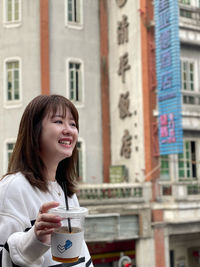 Portrait of young woman using mobile phone in city