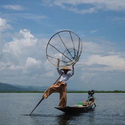 Man on boat in lake against sky