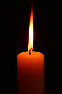 Close-up of lit candle in darkroom