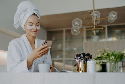 Young woman with eye patch using mobile phone at home