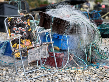 Folding chair by fishing nets in crate on pebbles at beach
