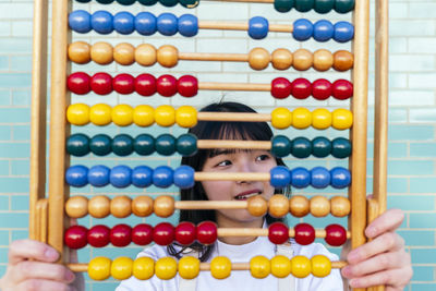Thoughtful woman with multi colored abacus in front of brick wall