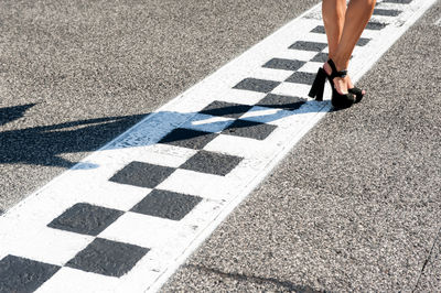 Low section of woman standing on finish line at motor racing track