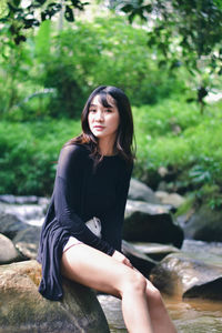 Portrait of young woman sitting on rock