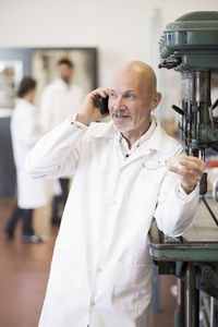 Engineer answering mobile phone with colleagues in background at industry